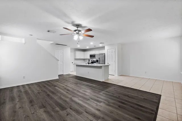 a view of an empty room with a kitchen and a window