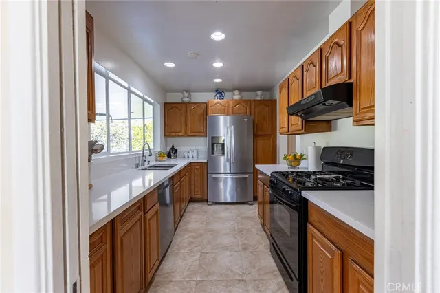 a kitchen with stainless steel appliances granite countertop a stove a sink dishwasher a refrigerator and a oven with wooden floor