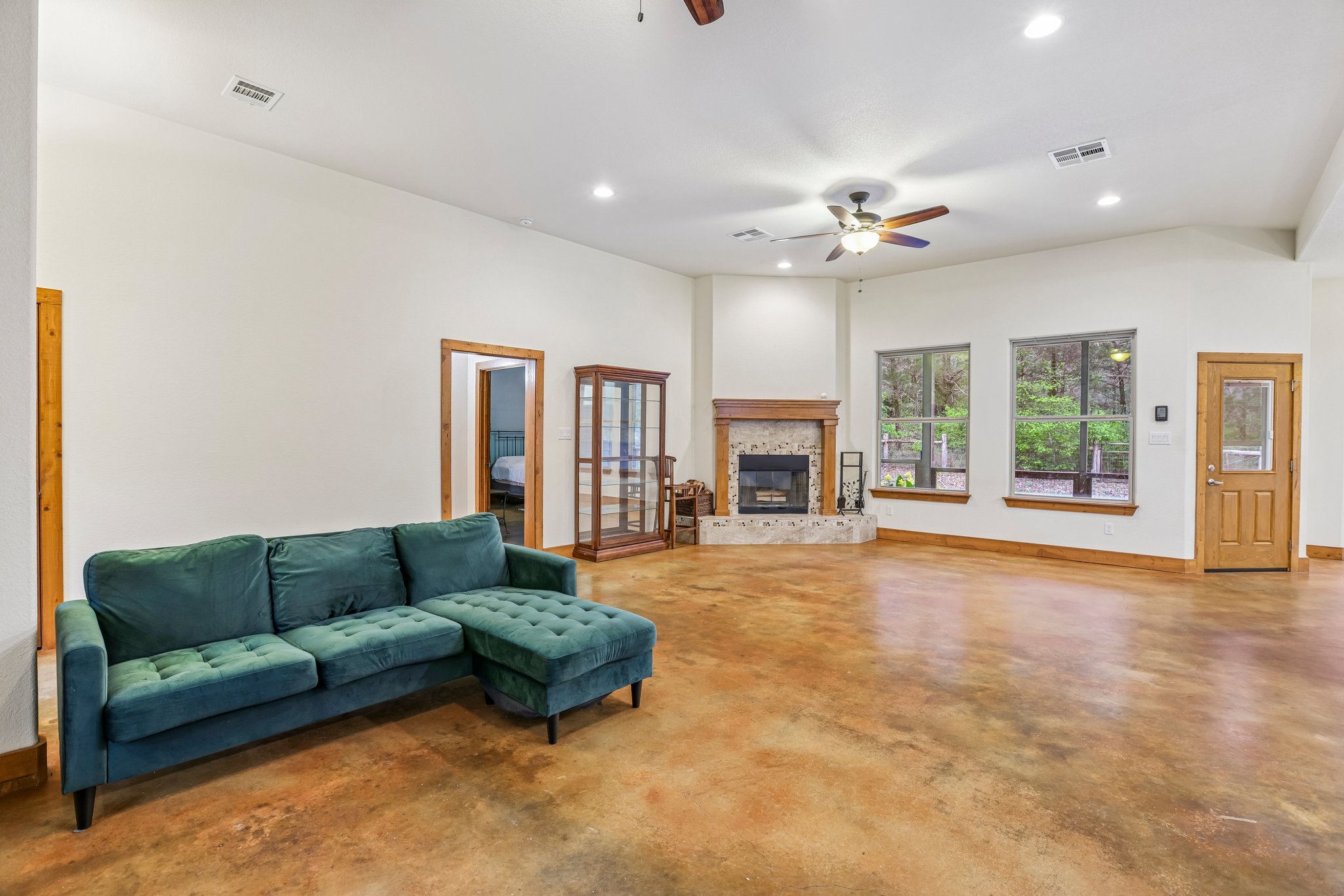267 Corral Road Smithville, TX 78957 - Photo 12 of 40 Spacious living area featuring stained concrete flooring, a corner fireplace with stone surround and wood mantel, recessed lighting, and multiple windows