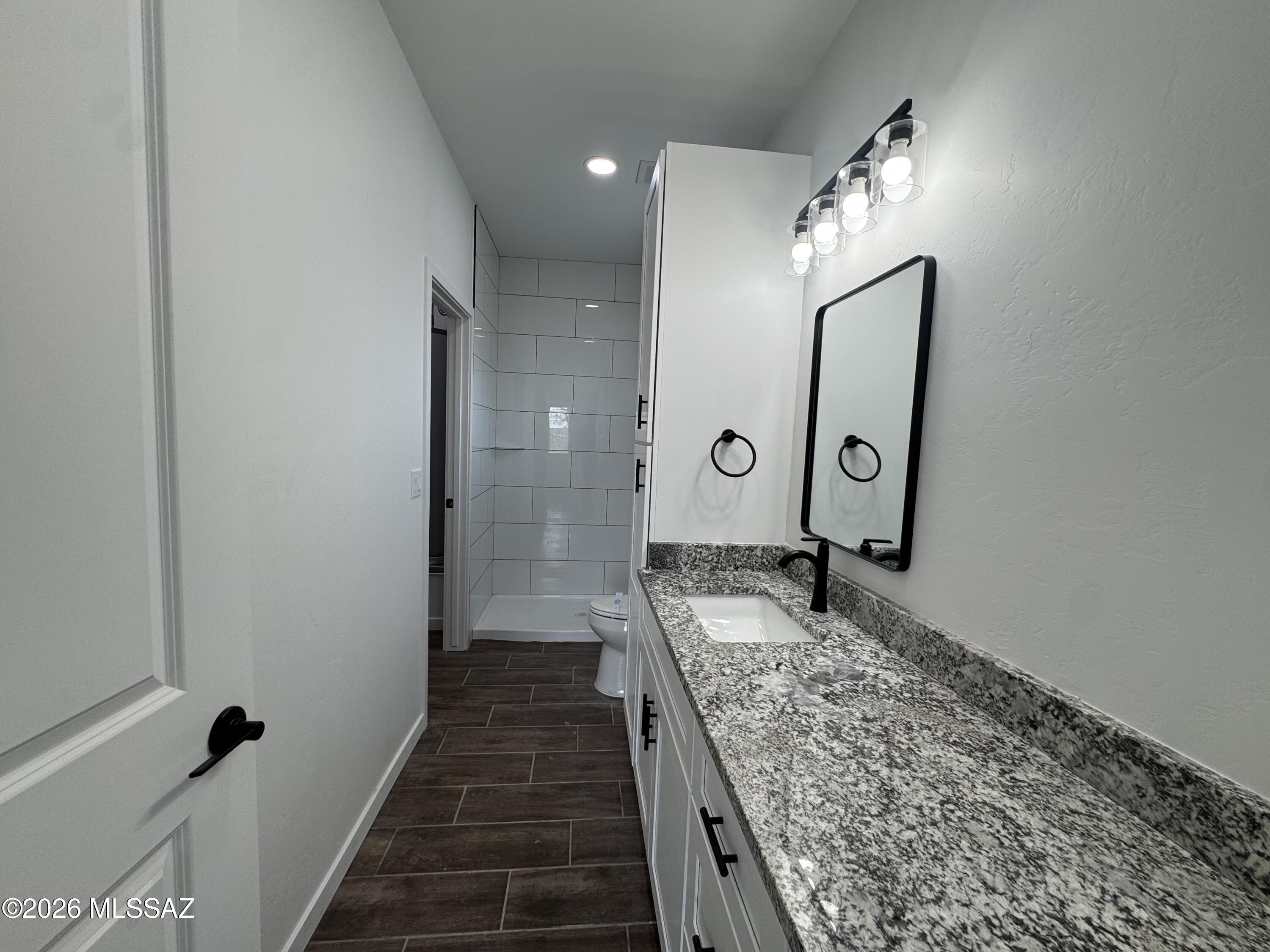 2122 North Ralph Avenue, Unit 1 Tucson, AZ 85712 - Photo 8 of 10 a bathroom with a granite countertop sink a mirror and shower