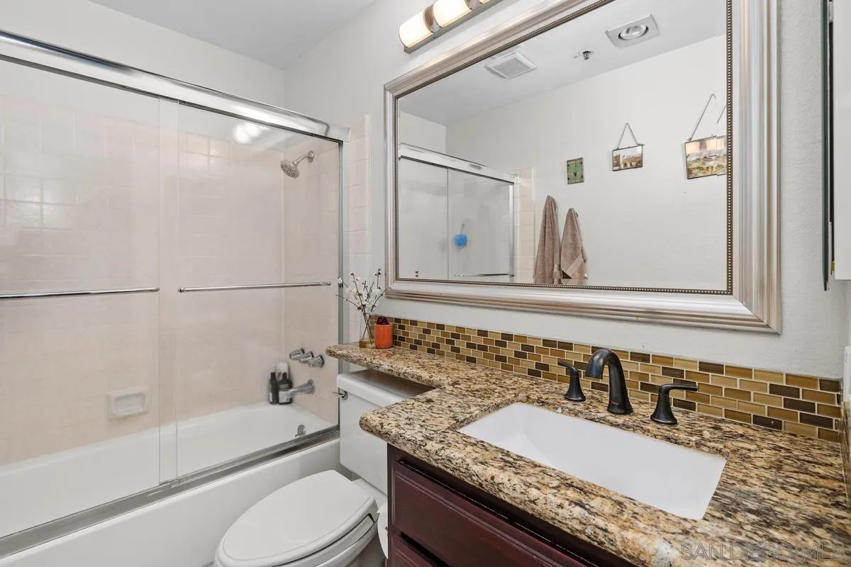 5605 Friars Road, Unit 308 San Diego, CA 92110 - Photo 23 of 39 a bathroom with a granite countertop sink mirror vanity and toilet
