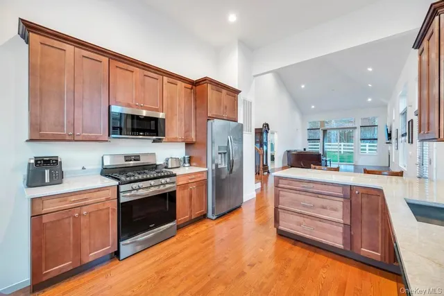 a kitchen with stainless steel appliances granite countertop a stove top oven a sink and dishwasher a refrigerator with wooden floor