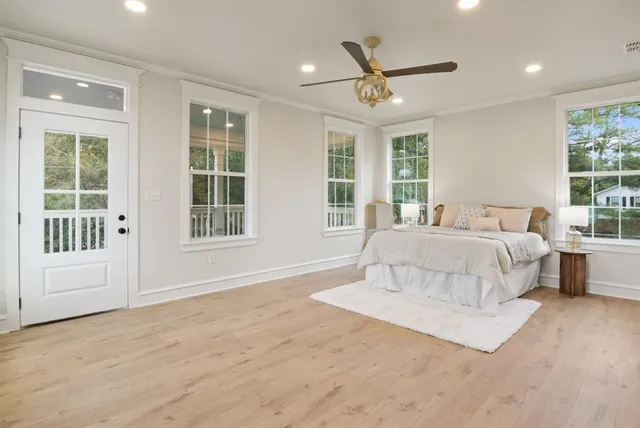 a spacious bedroom with a large bed chandelier and windows