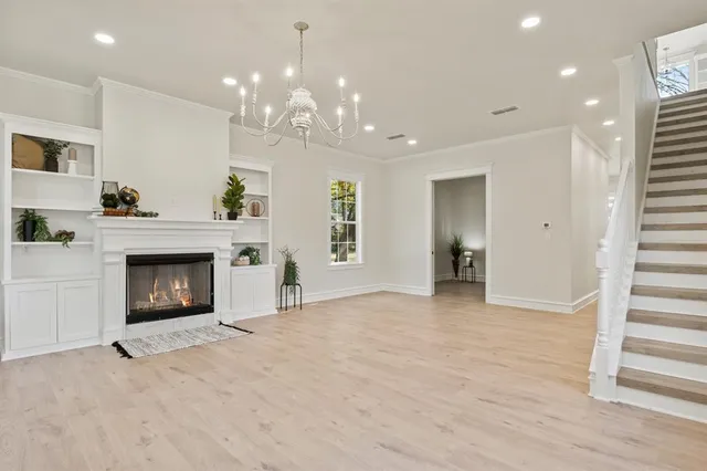 a view of an empty room with fireplace and wooden floor