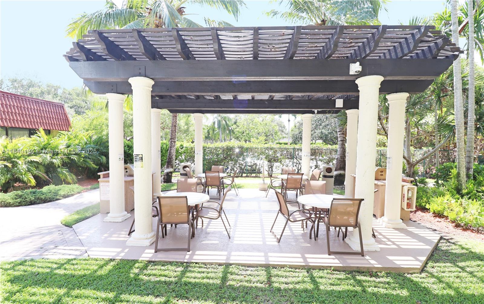9301 Southwest 92nd Avenue, Unit A210 Miami, FL 33176 - Photo 24 of 25 a view of a patio with table and chairs potted plants and floor to ceiling window