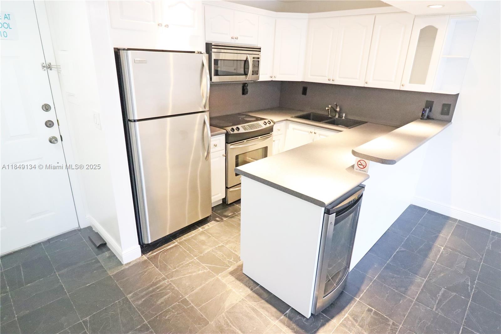 9301 Southwest 92nd Avenue, Unit A210 Miami, FL 33176 - Photo 8 of 25 a kitchen with a refrigerator a sink and cabinets