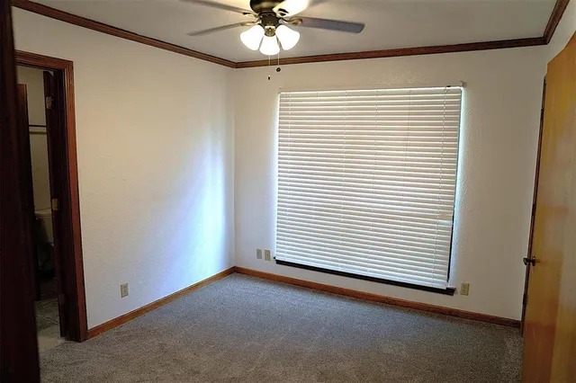 an empty room with a ceiling fan and a window