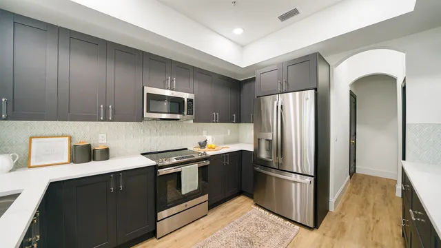 a kitchen with stainless steel appliances granite countertop a refrigerator a stove a sink and a microwave