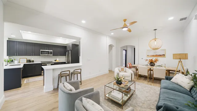 a living room with furniture kitchen view and a chandelier