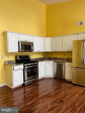 a kitchen with granite countertop a refrigerator stove and wooden floor