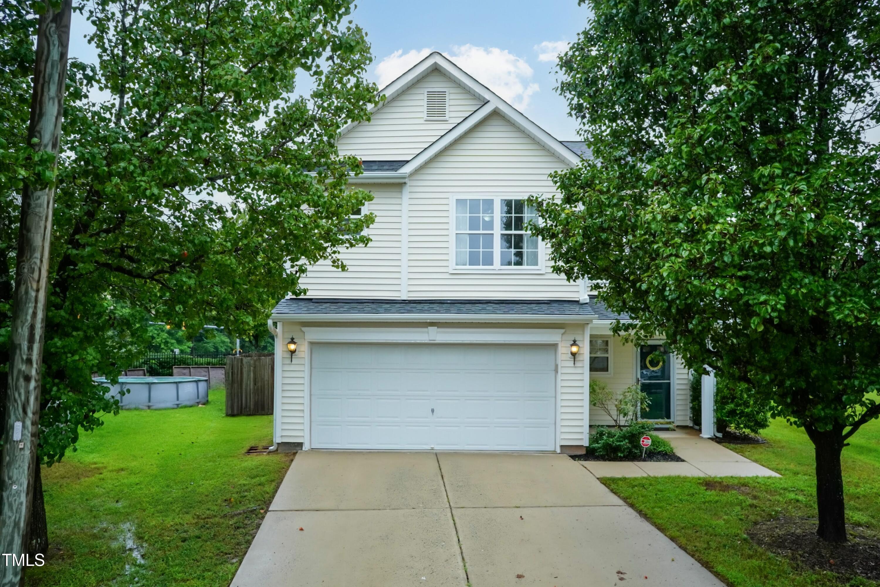 a front view of a house with a garden and trees