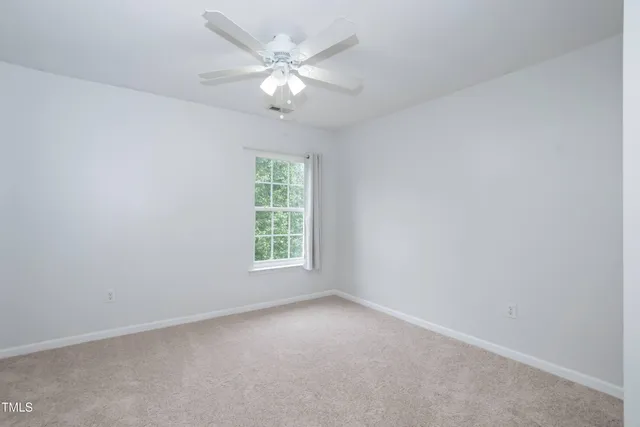 an empty room with a chandelier fan and windows