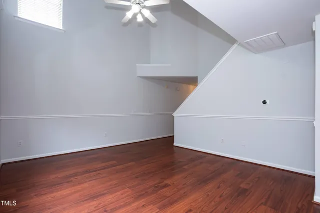 an empty room with wooden floor and chandelier fan