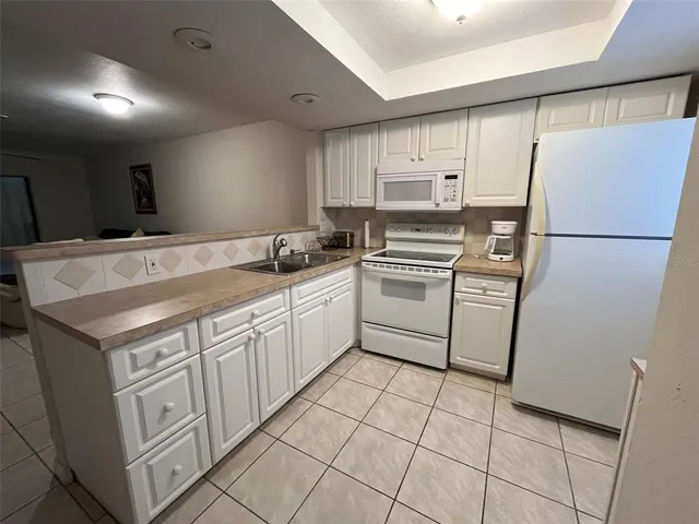 a kitchen with a sink a stove a refrigerator and white cabinets