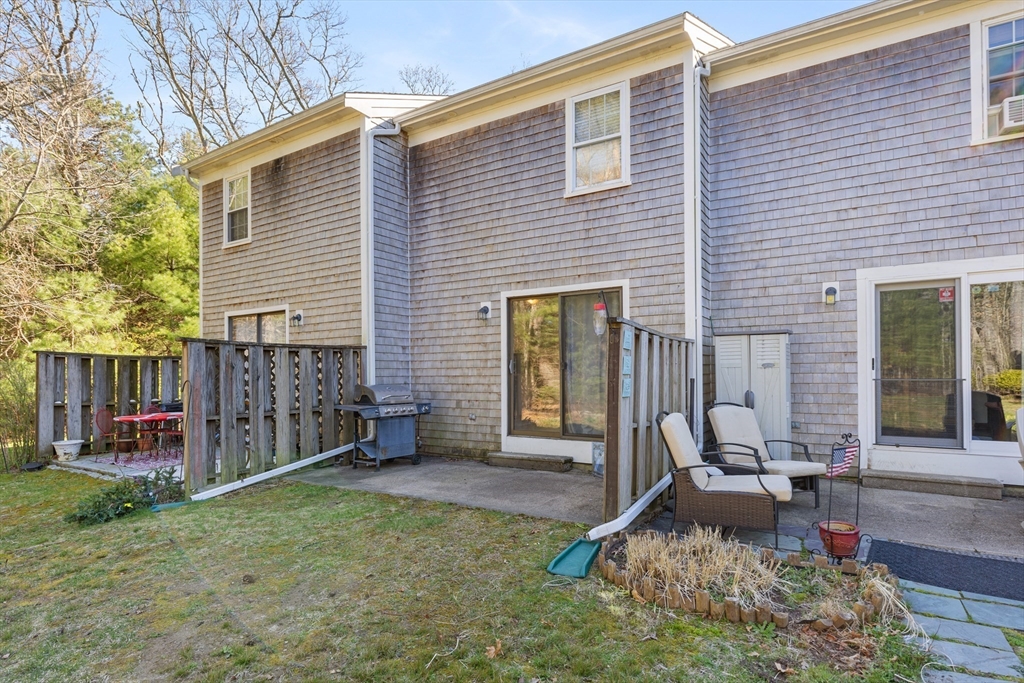 300 Falmouth Road, Unit 20D Mashpee, MA 02649 - Photo 2 of 20 a backyard of a house with barbeque oven table and chairs
