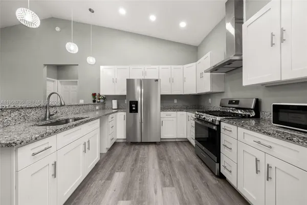 a kitchen with granite countertop a sink a counter top space stainless steel appliances and cabinets