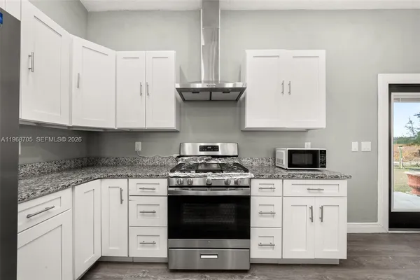 a kitchen with stainless steel appliances a stove a white cabinets and a wooden floor