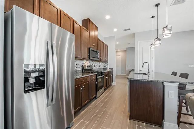 a kitchen with stainless steel appliances a refrigerator a stove a sink dishwasher and a refrigerator with wooden floor