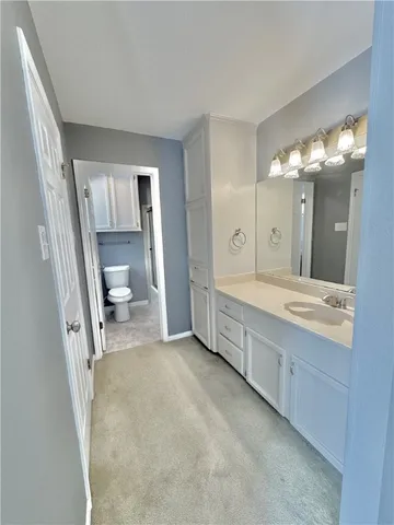 a spacious bathroom with a granite countertop sink mirror and a toilet