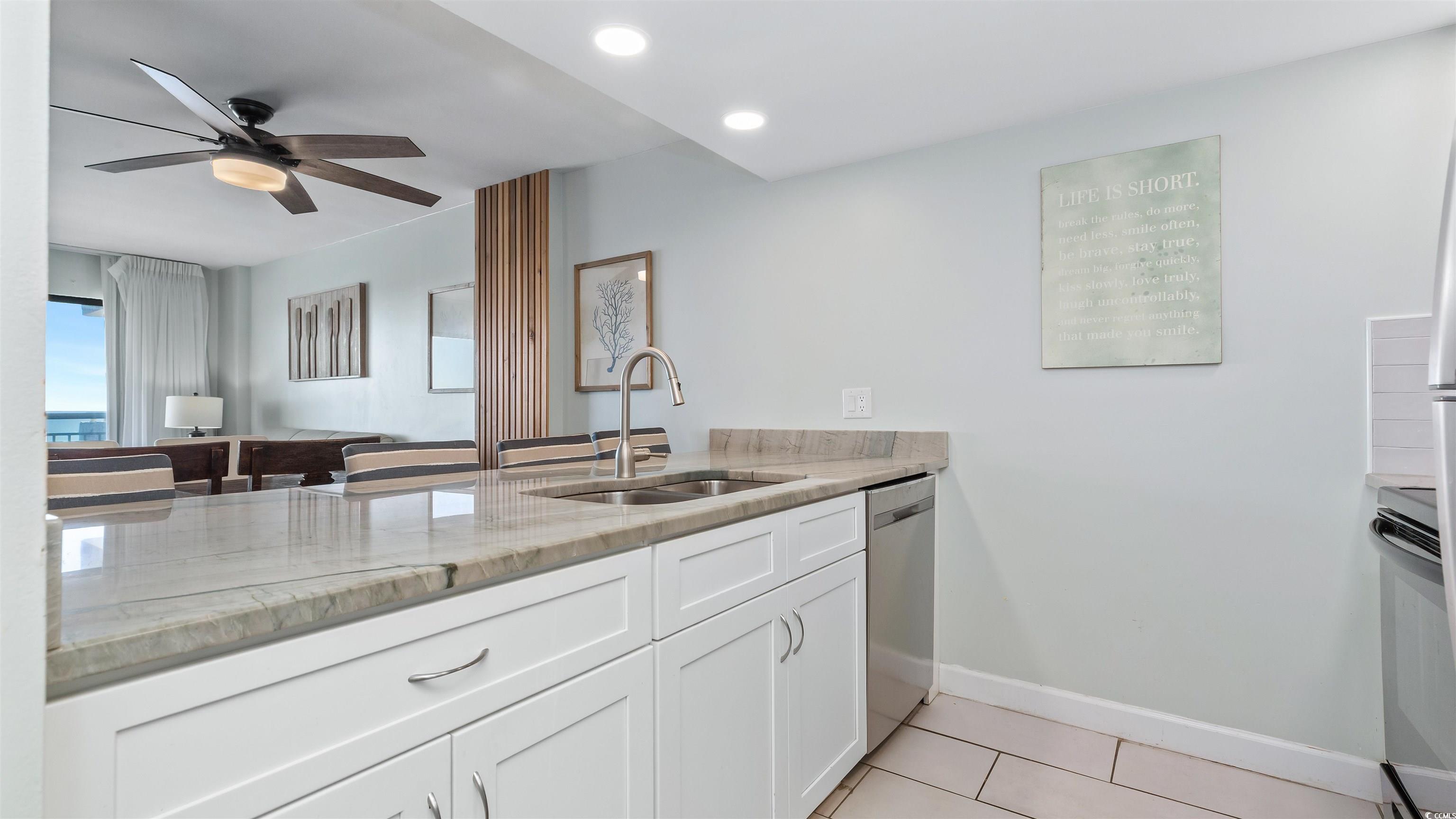 2001 South Ocean Boulevard, Unit 603 Myrtle Beach, SC 29577 - Photo 22 of 33 Kitchen featuring light tile patterned flooring, white cabinetry, range, light stone countertops, and dishwasher