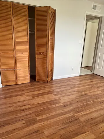 an empty room with wooden floor and entrance