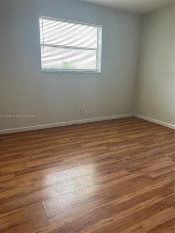an empty room with wooden floor and a window