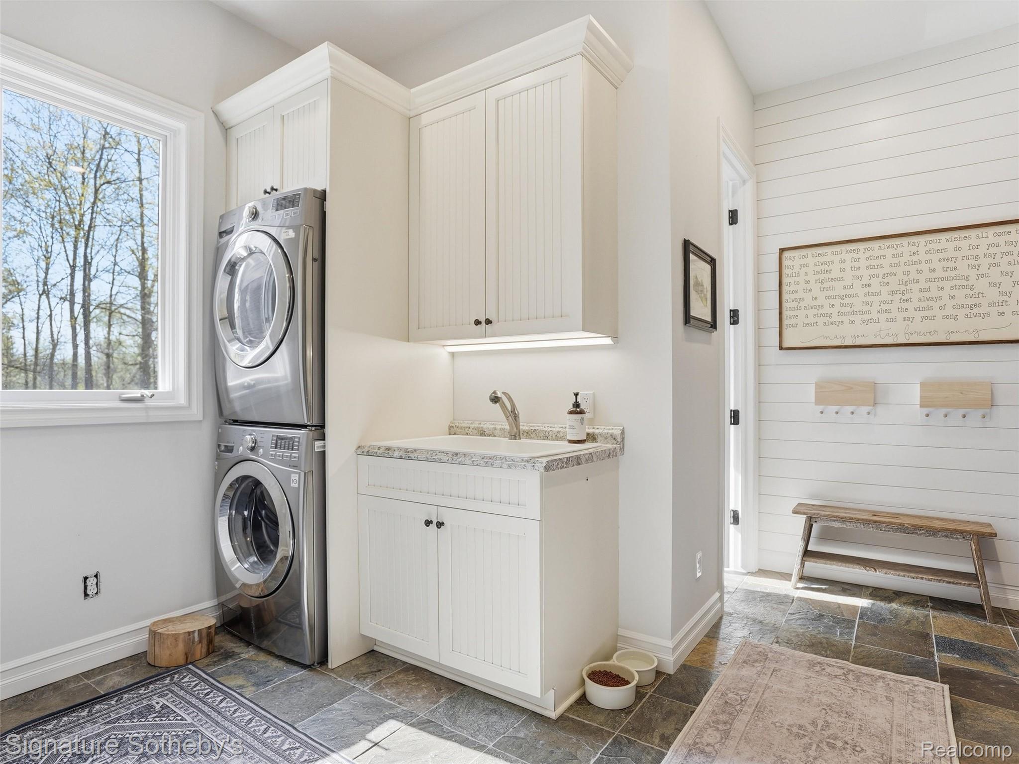 1595 Carriage Way Rochester, MI 48307 - Photo 75 of 78 Laundry room with stone tile floors, stacked washer / dryer, wooden walls, and cabinet space