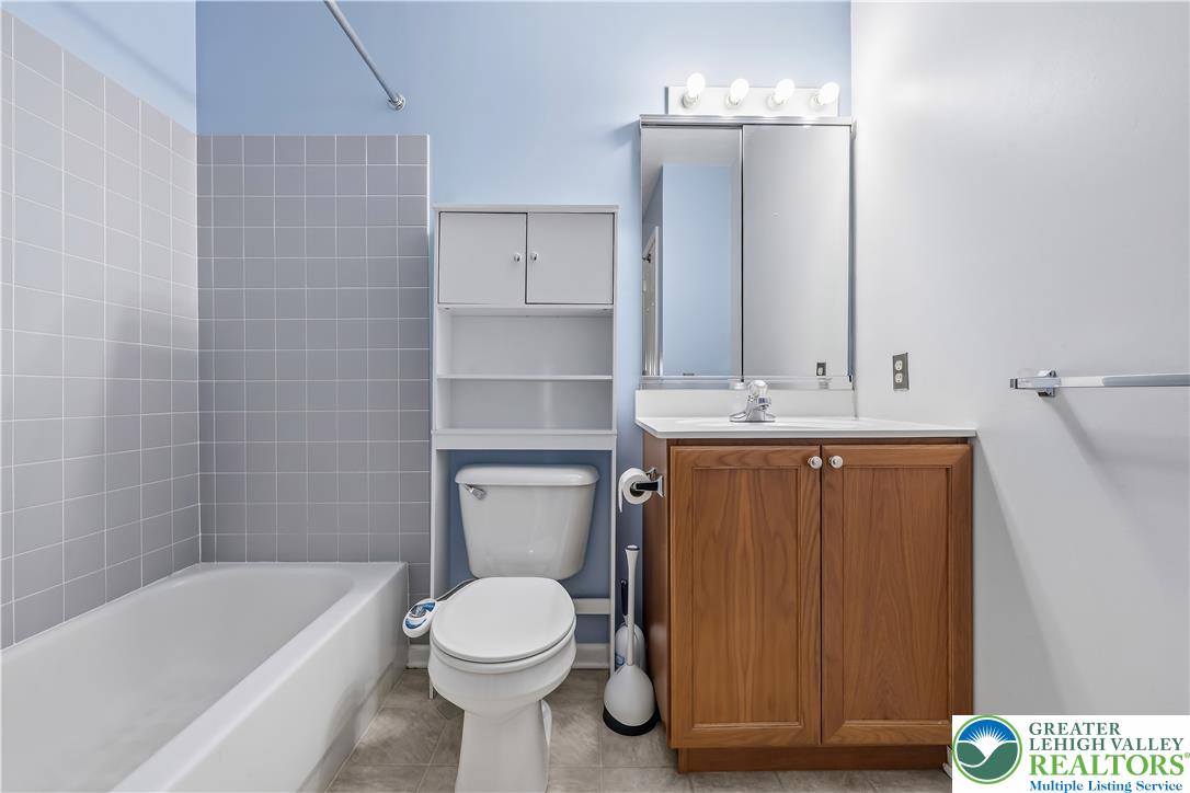 5607 Spring Ridge Drive West Macungie, PA 18062 - Photo 20 of 26 A classic wood vanity and tiled bath tub enclosure anchor this functional bathroom.