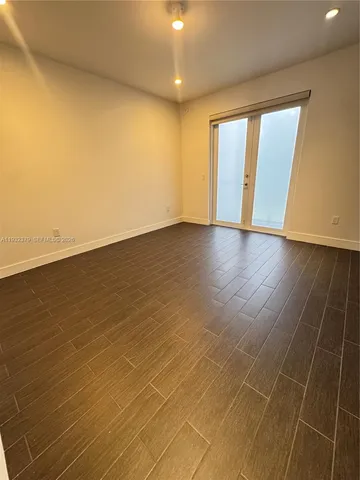 an empty room with wooden floor and windows with curtains