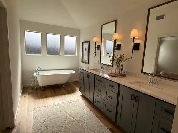 a spacious bathroom with a double vanity sink a mirror and a toilet