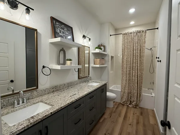 a bathroom with a granite countertop sink a mirror and a toilet