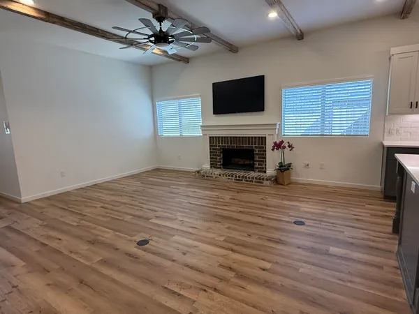 a view of empty room with wooden floor fireplace and a window