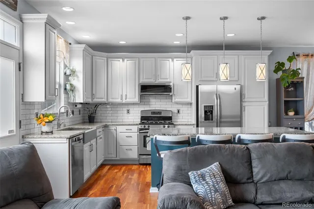 a kitchen with stainless steel appliances granite countertop a refrigerator a stove and a sink