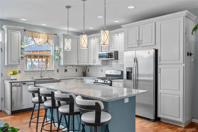 a kitchen with stainless steel appliances granite countertop a table chairs sink refrigerator and microwave