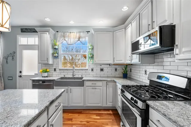 a kitchen with stainless steel appliances granite countertop a stove a sink and a microwave
