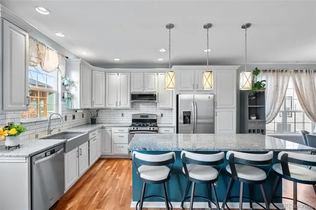 a large kitchen with kitchen island granite countertop lots of wooden cabinets stainless steel appliances a dining table and chairs