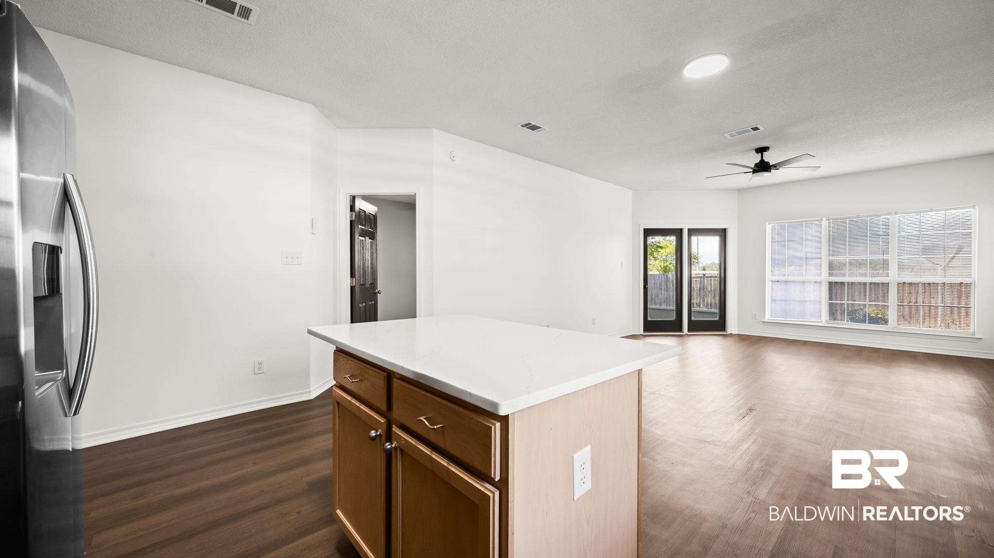 2651 South Juniper Street, Unit 705 Foley, AL 36535 - Photo 6 of 37 Central kitchen island with a light-toned countertop, wood-finish cabinetry, and stainless steel refrigerator