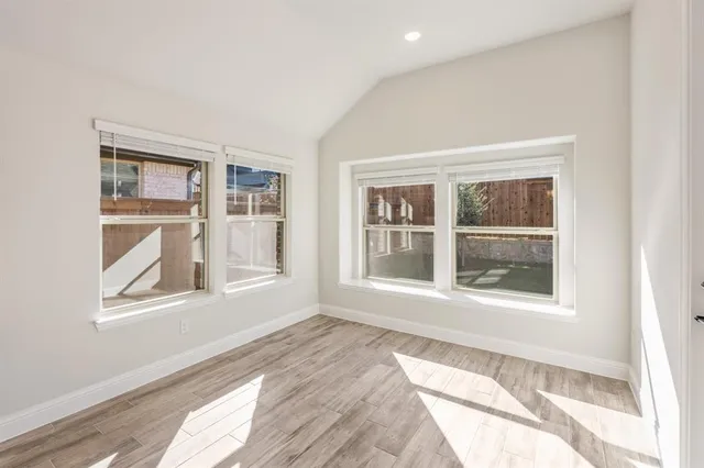 a view of an empty room with a window and wooden floor