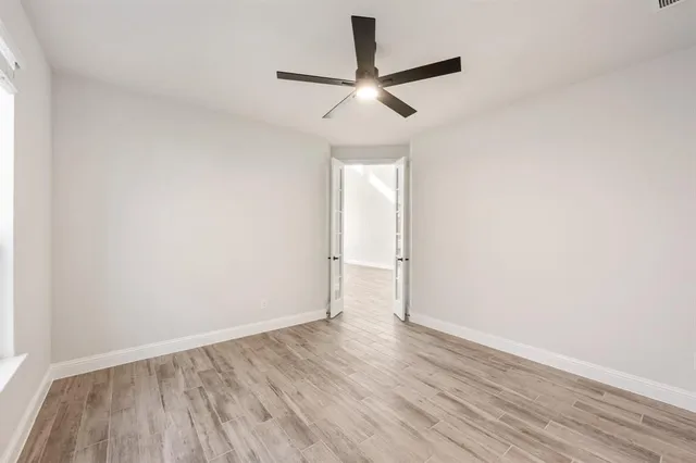 an empty room with wooden floor and a ceiling fan