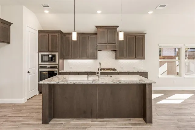 a view of a kitchen with kitchen island a counter top space stainless steel appliances and wooden floor