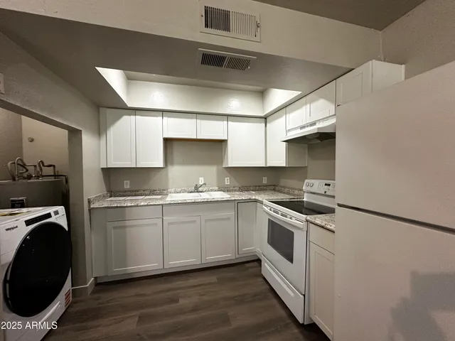 a kitchen with a stove white cabinets and a sink