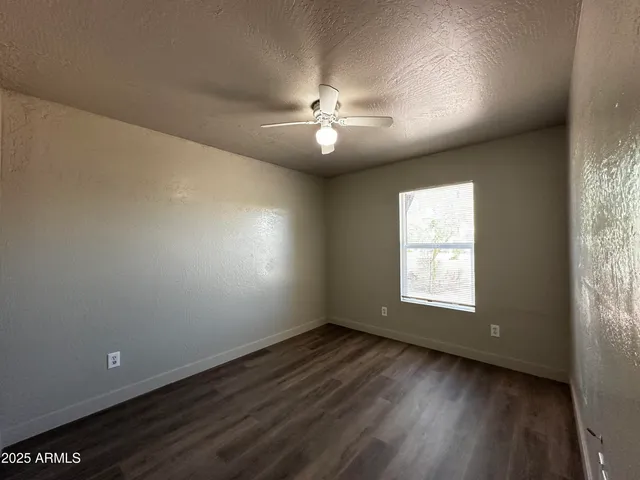an empty room with wooden floor ceiling fan and windows
