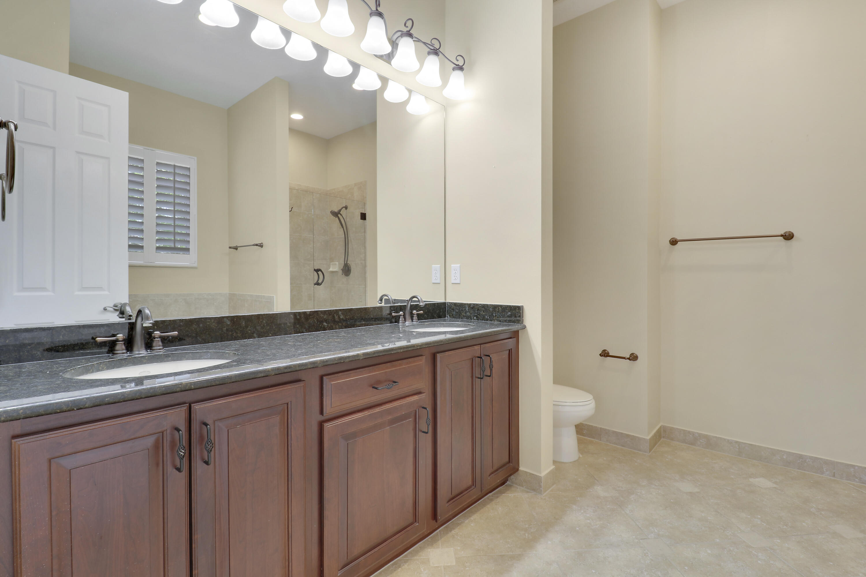 138 Tallow Trail Jupiter, FL 33458 - Photo 22 of 38 a bathroom with a granite countertop sink a large mirror and a toilet