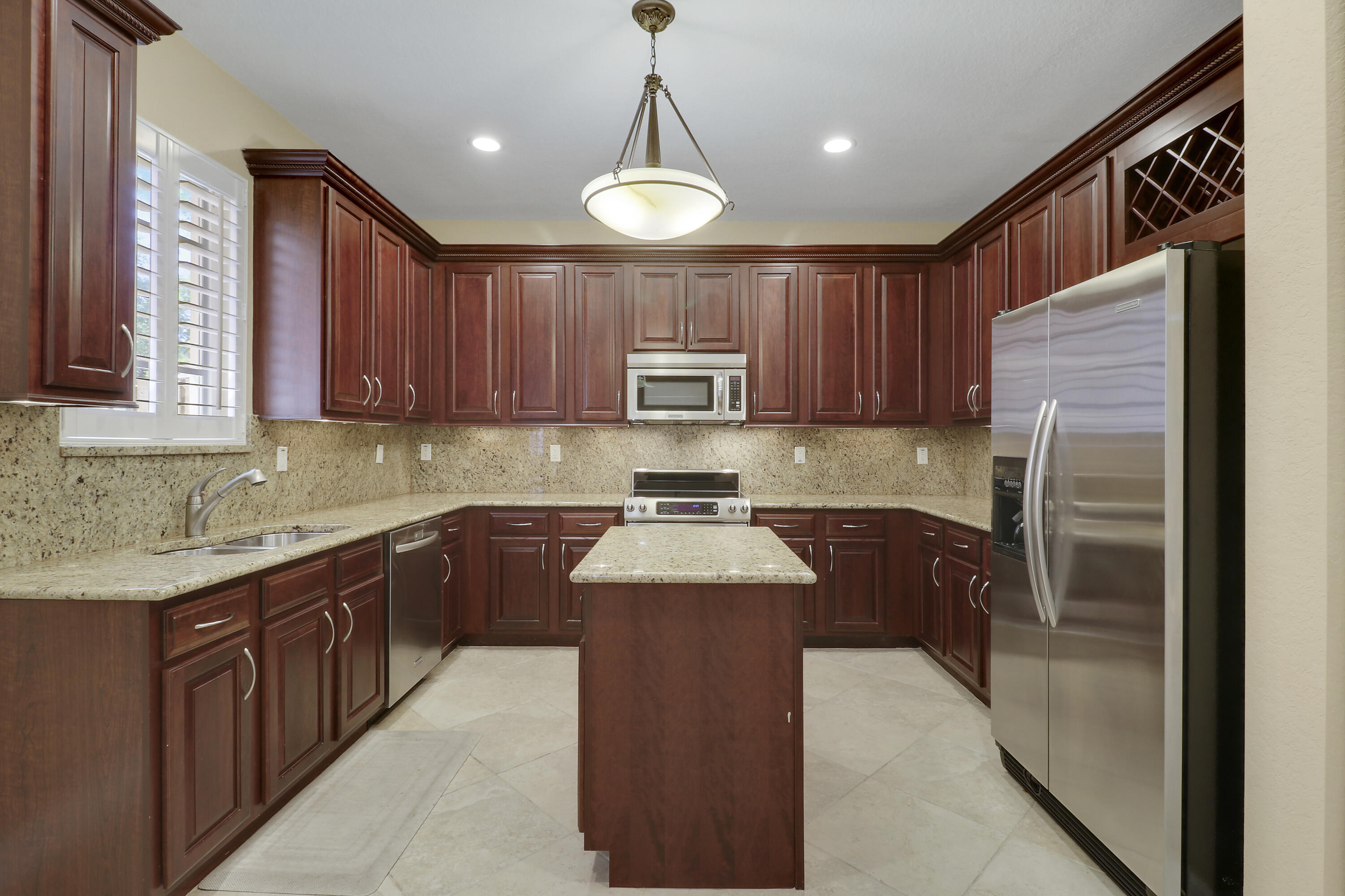 138 Tallow Trail Jupiter, FL 33458 - Photo 10 of 38 a kitchen with stainless steel appliances granite countertop wooden cabinets a stove a sink and a granite counter top