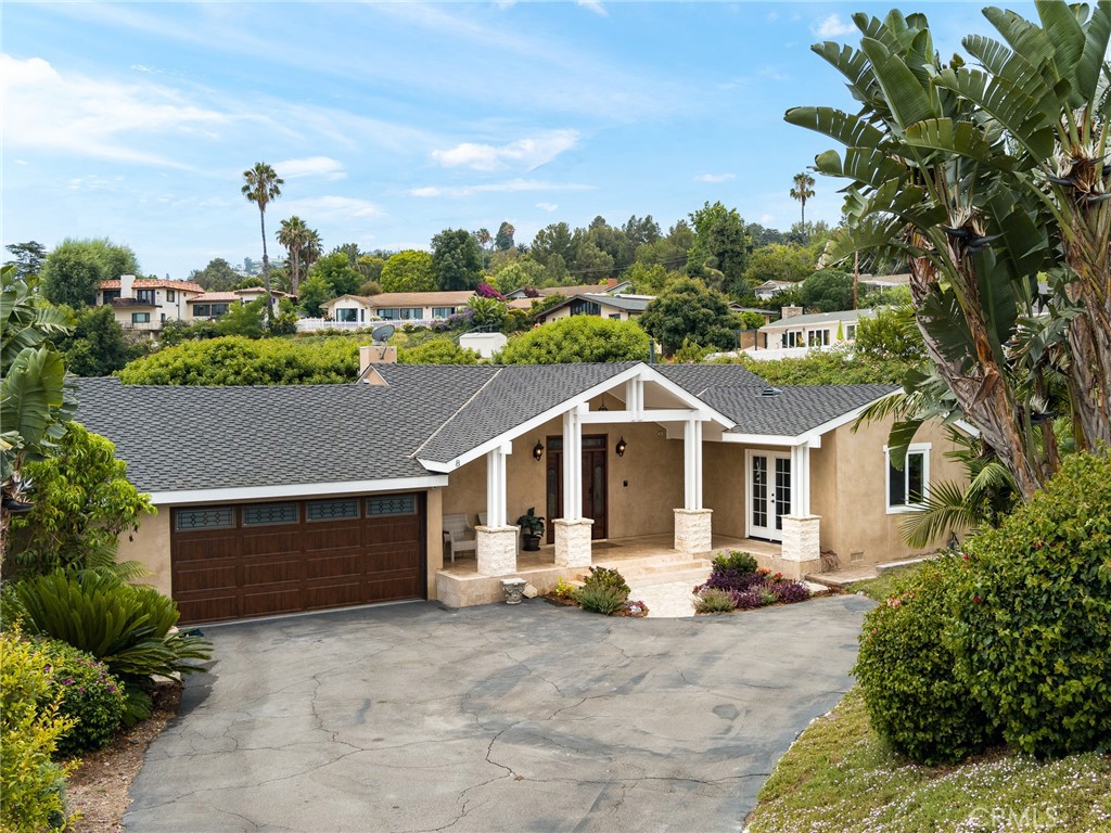 a view of a white house with a big yard plants and large trees