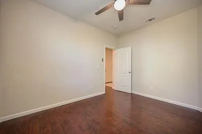 an empty room with wooden floor fan and windows
