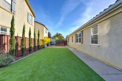 a view of a house with a yard and lawn chairs under an umbrella