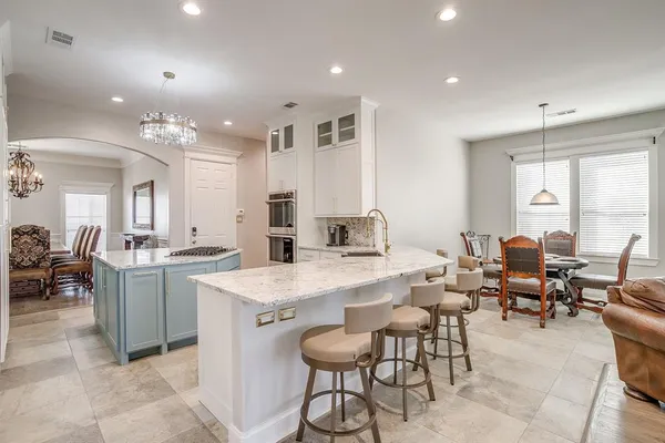 a large dining space with stainless steel appliances lots of white furniture a window and a refrigerator