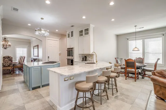 a large dining space with stainless steel appliances lots of white furniture a window and a refrigerator