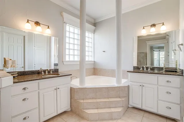 a bathroom with a granite countertop double vanity sink a mirror and a bathtub